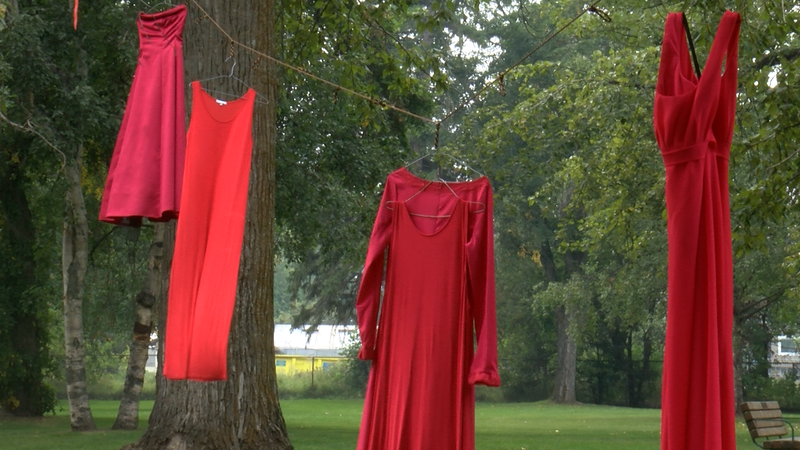4 red dresses hand on clothesline in between large trees